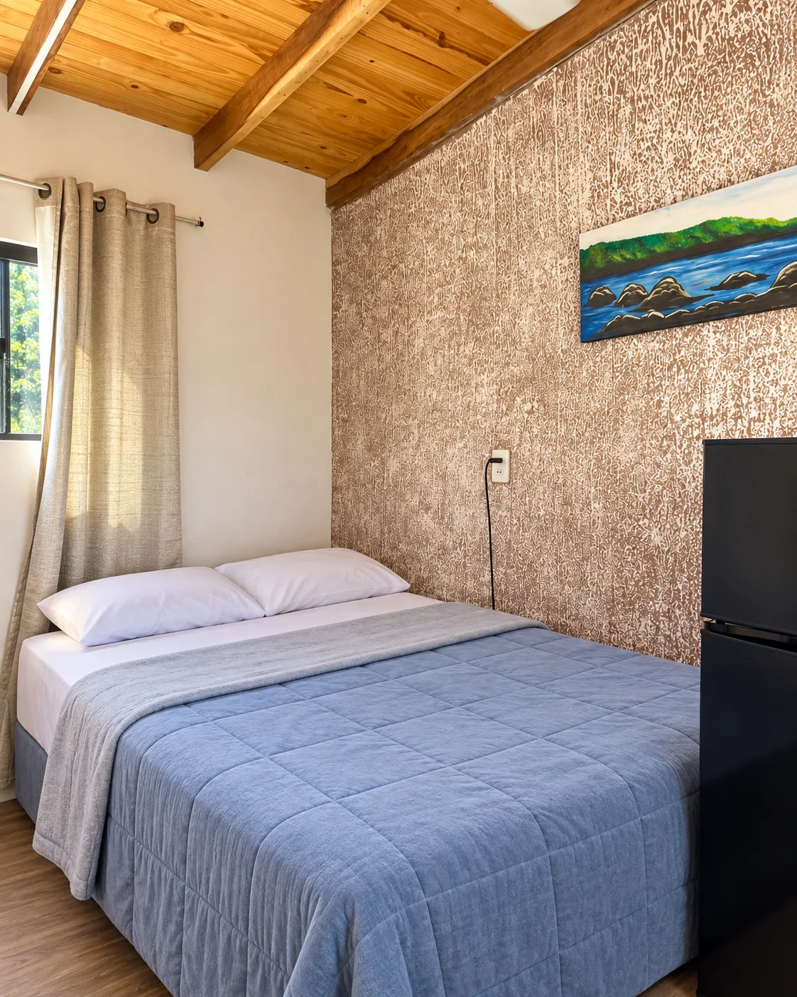 Segunda habitación con cama matrimonial, techo de madera y luz natural